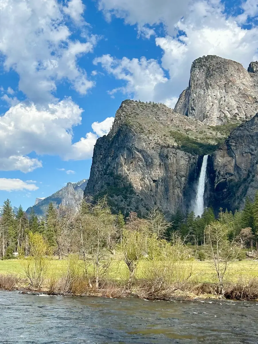 Bridalveil Fall on a granite cliff above the Merced River and a green meadow